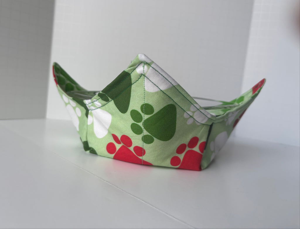 Green fabric bowl with paw print pattern on a white surface