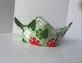 Green fabric bowl with paw print pattern on a white surface