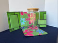 Clear glass tumbler with floral design on a green floral holder against a white background