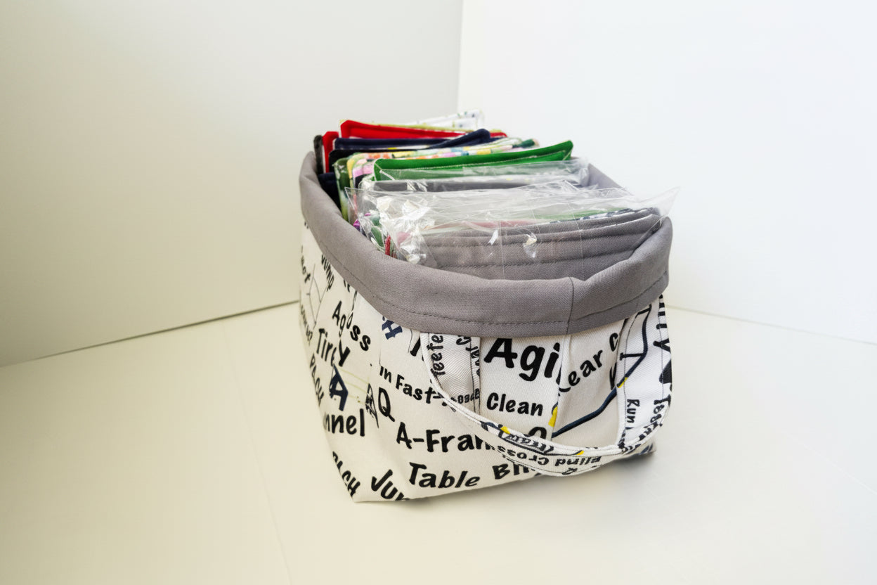 A fabric storage basket with a gray fabric lining and a white printed fabric exterior featuring black text and diagrams. The basket is filled with fabric coasters. 