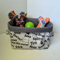 A fabric storage basket with a gray interior and a white exterior printed with black automotive terms like 'MACH', 'Tire', 'Jump', and 'Agility'.