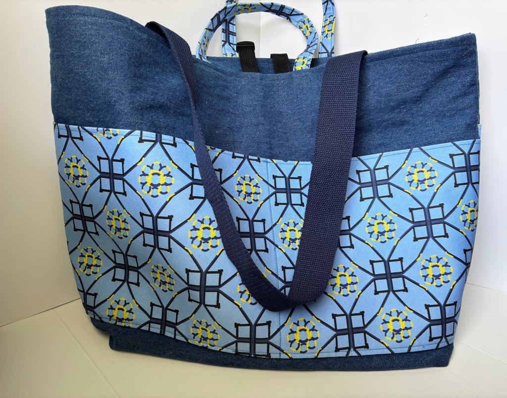 A large tote bag with a blue and navy patterned front panel and solid navy blue top and handles, photographed against a plain light background.