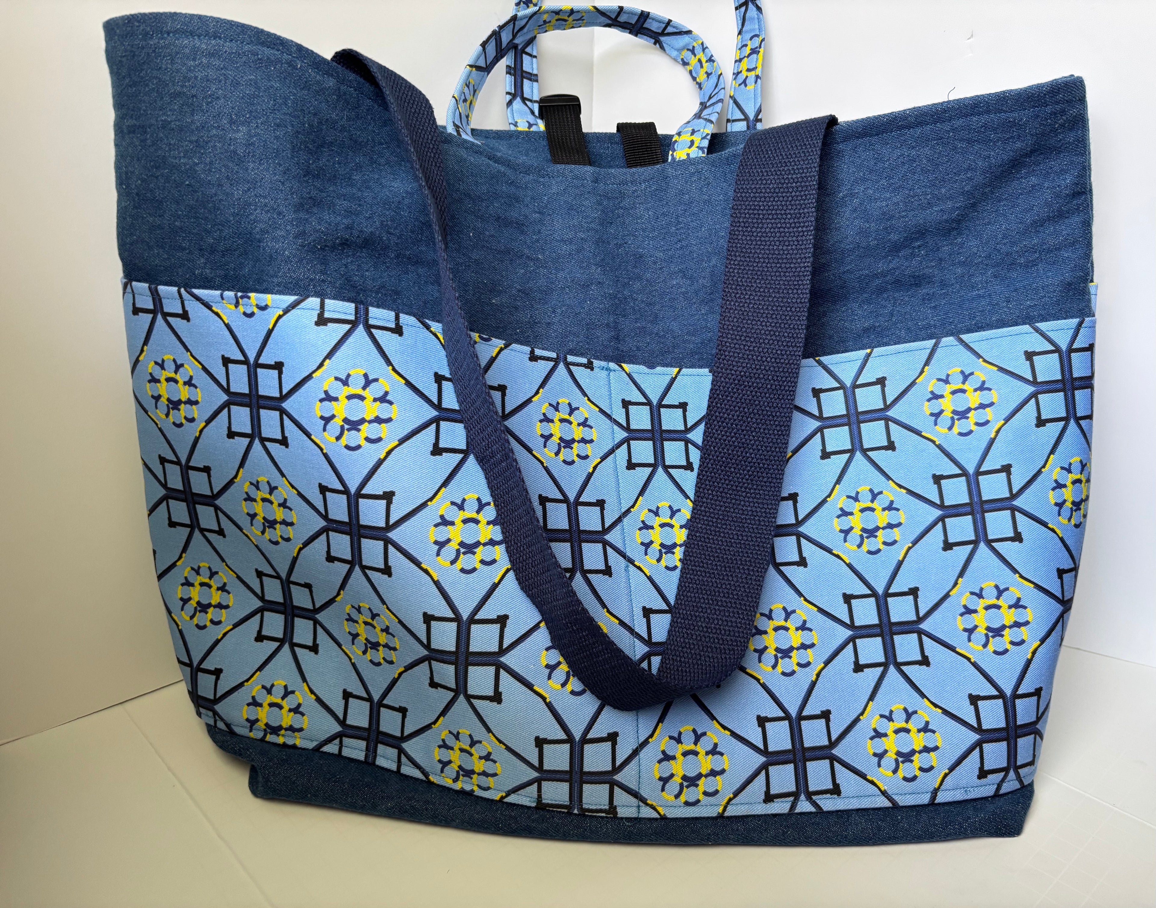 A large tote bag with a blue and navy patterned front panel and solid navy blue top and handles, photographed against a plain light background.