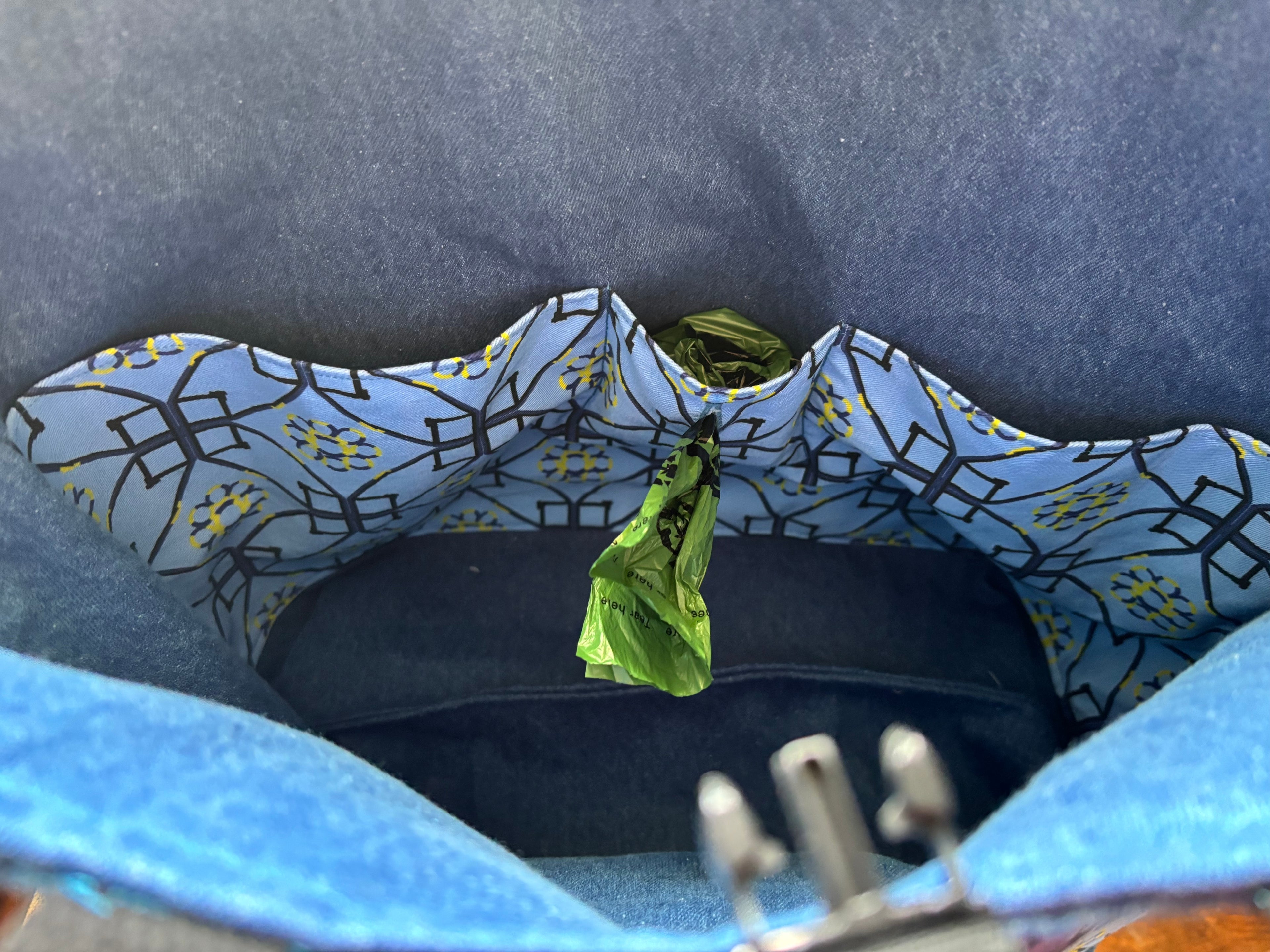 Close-up of the inside of a blue denim bag and with poop bag roll pocket.